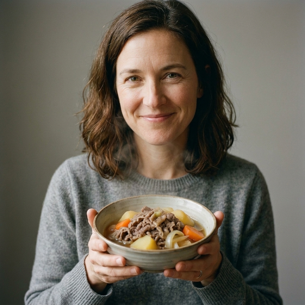 A small bowl of nikujaga with thin slices of beef, potatoes, carrots, and onions in a light soy-based broth